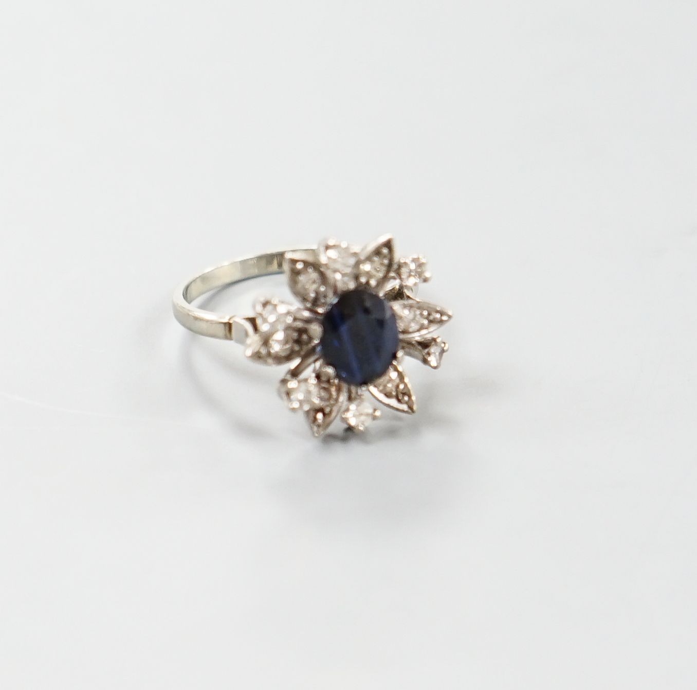 A 1930's 18ct white gold, sapphire and diamond cluster set flower head ring, size Q/R